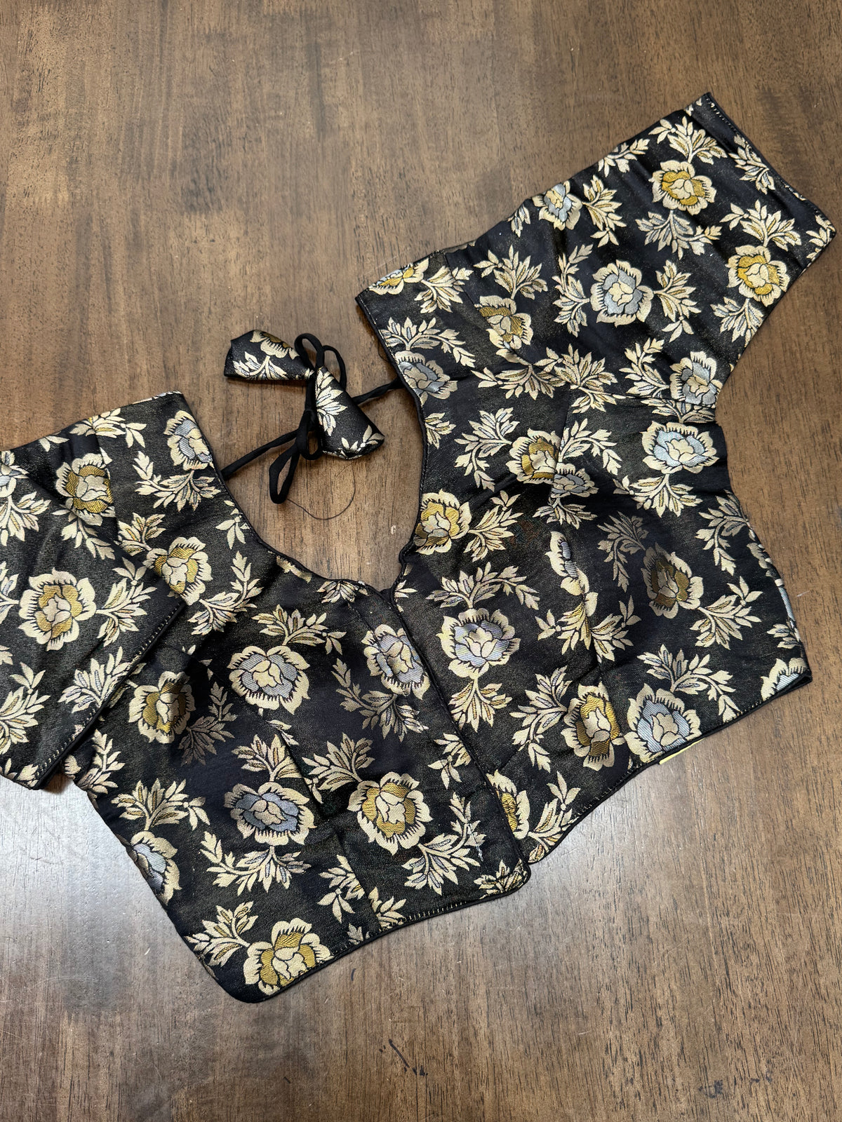This elegant black floral brocade blouse adds soft shimmer and depth, making it a perfect match for silk, Banarasi, and Kanchipuram sarees.