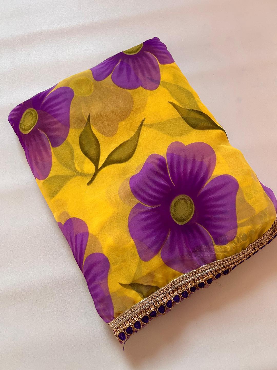 Yellow fabric with purple floral patterns on a white background