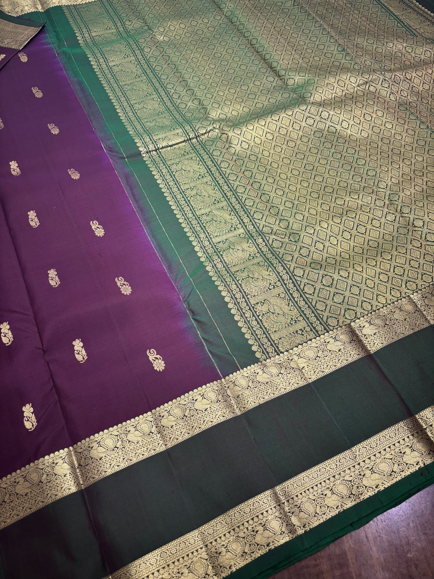 "Close-up of gold zari work on burgundy Kanchipuram silk saree showing detailed temple border pattern and traditional motifs"