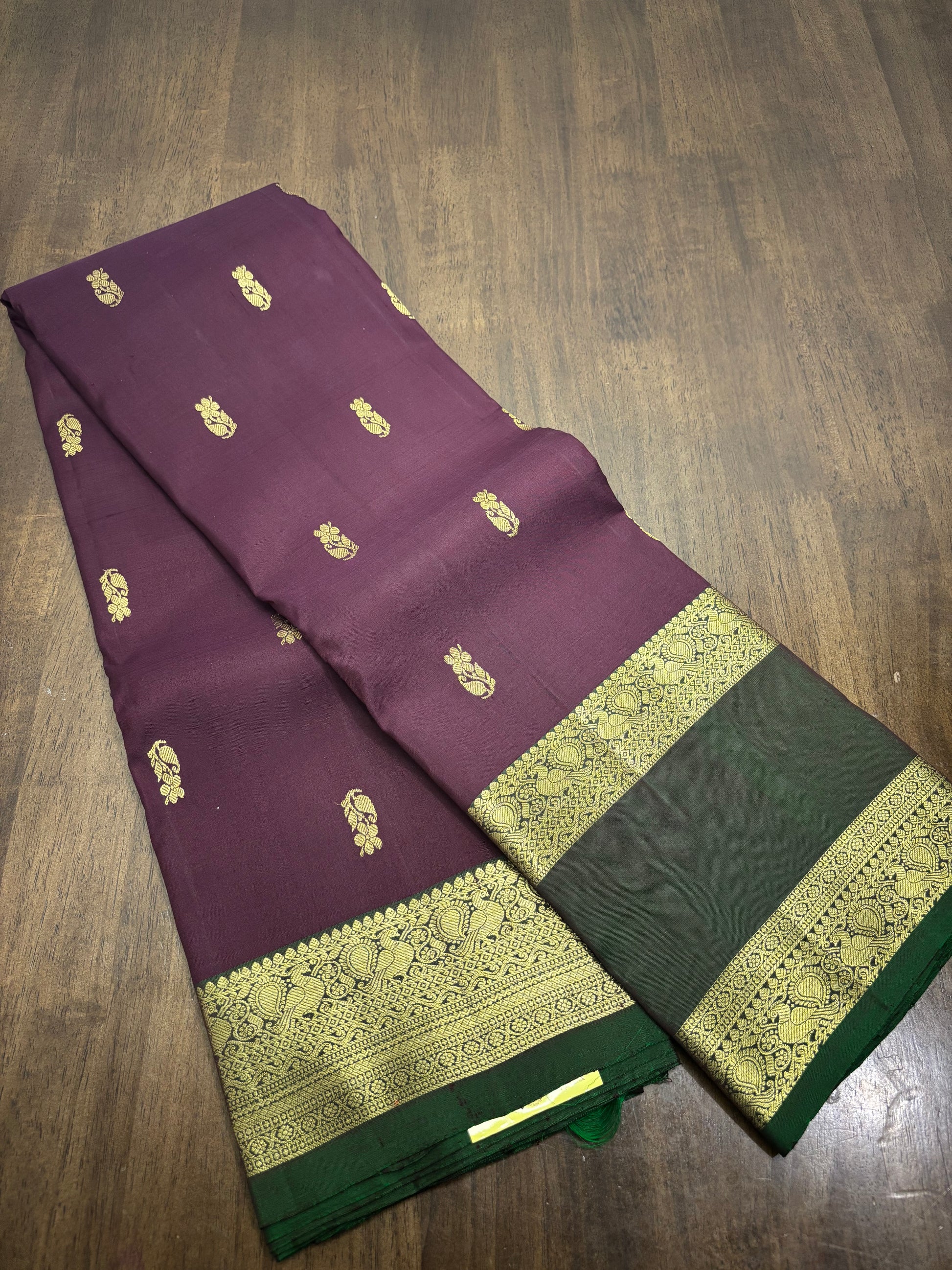 "Burgundy and green Kanchipuram silk saree with gold zari work displayed in full length, showing intricate border and pallu design"