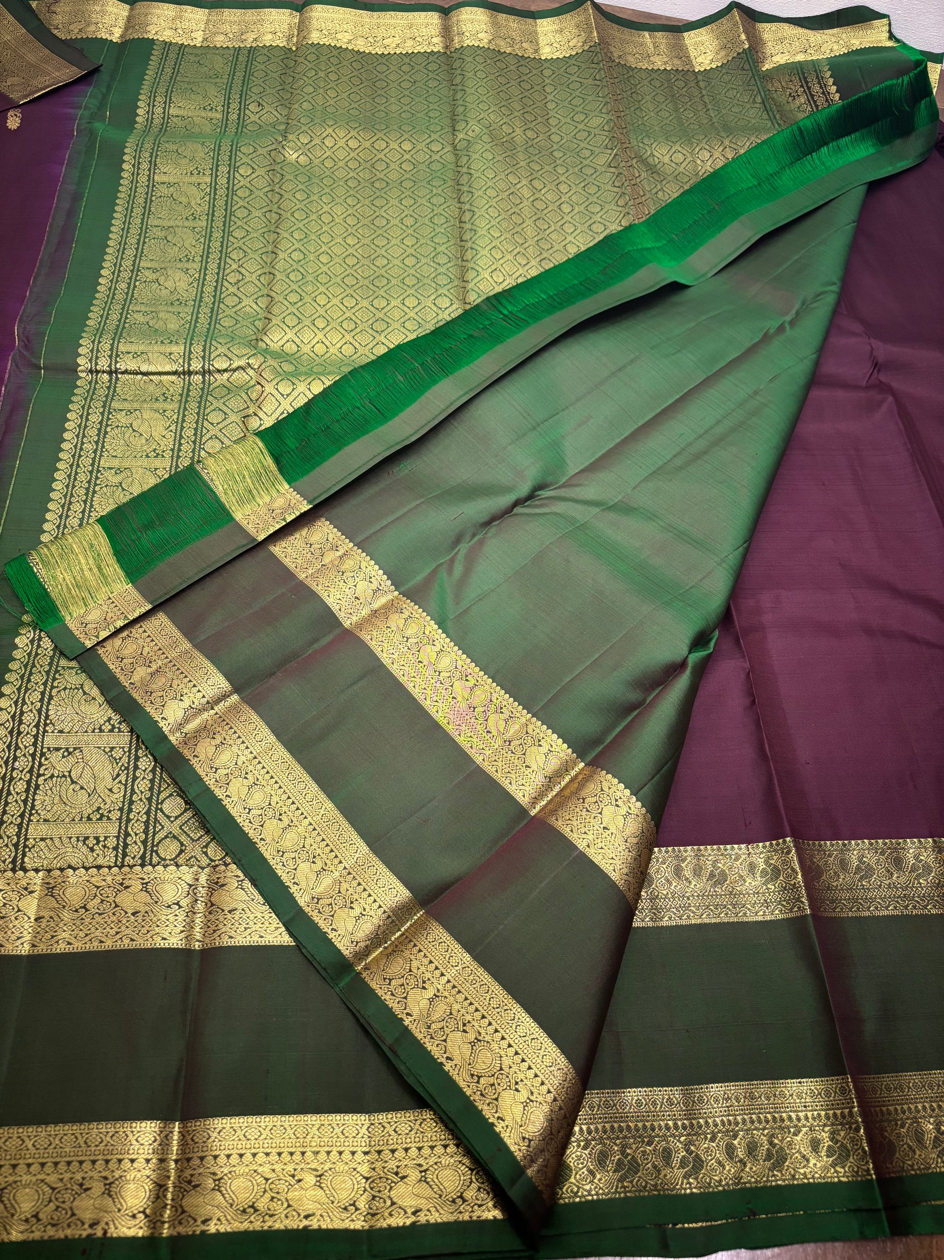 "Burgundy and green Kanchipuram silk saree draped on model showing elegant fall and contrast border design"
