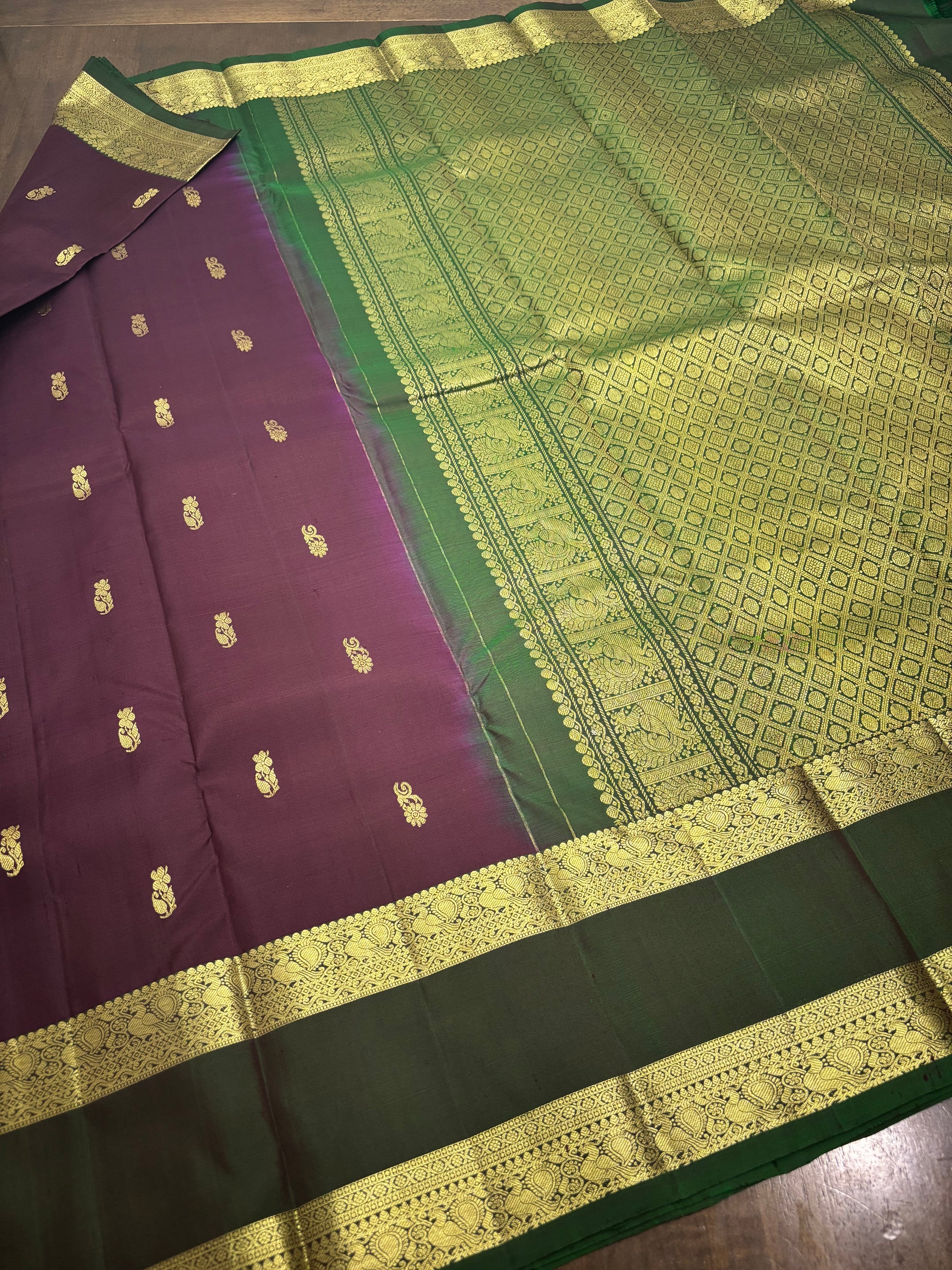 "Burgundy and green Kanchipuram silk saree draped on model showing elegant fall and contrast border design"